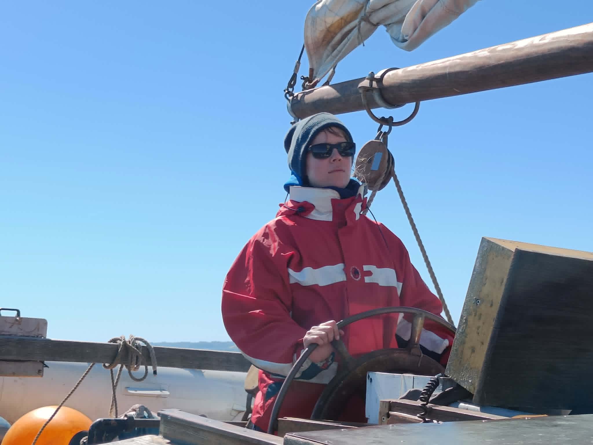 Student at the helm of a traditional sailing vessel during a Seamanship Academy sail training course near Flensburg